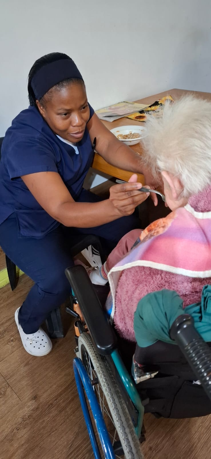 Caregiver gently assisting a client during a meal